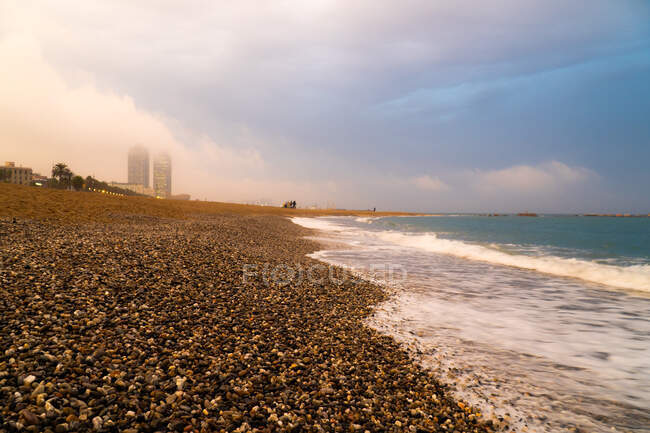 Peaceful landscape of empty city seaside and turquoise foamy waves under cloudy sky in bright day — Stock Photo