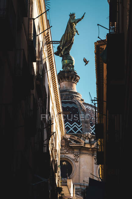 Von unten glänzende antike Statue mit erhobener Hand auf Kuppel der Konstruktion in einer Sackgasse zwischen Häusern — Stockfoto