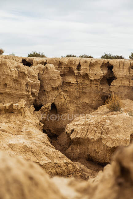 Grandes roches sèches avec végétation verte clairsemée sous le ciel bleu et nuages blancs à Bardenas Reales, Navarre, Espagne — Photo de stock