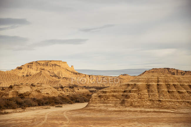 Dried big rocks with green sparse vegetation under blue sky and white clouds in Bardenas Reales, Navarre, Spain — Stock Photo