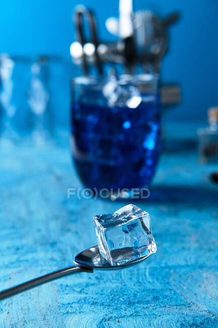 Eiswürfel pur auf Barmann-Löffel und blauer Cocktail im Glas auf dem Tisch — Stockfoto