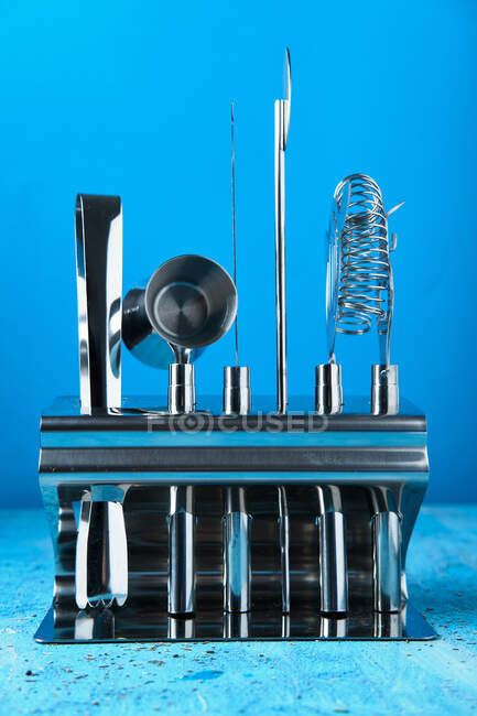 Conjunto moderno de acero inoxidable de equipo de barman arreglado en soporte sobre mesa azul - foto de stock