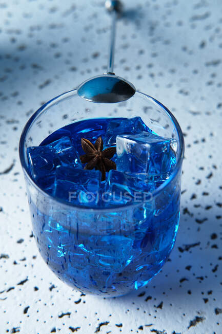 Von oben leuchtend blaues Getränk mit Eiswürfeln im Glas mit Barmann-Löffel auf dem Tisch — Stockfoto