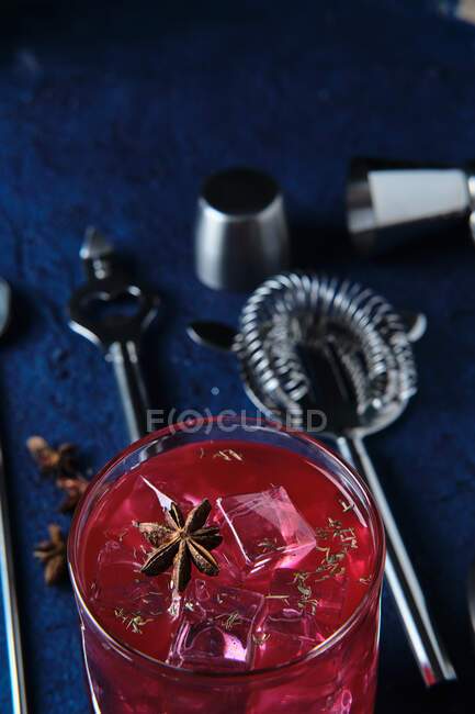 Delicious red cocktail and barman tools on table — Stock Photo