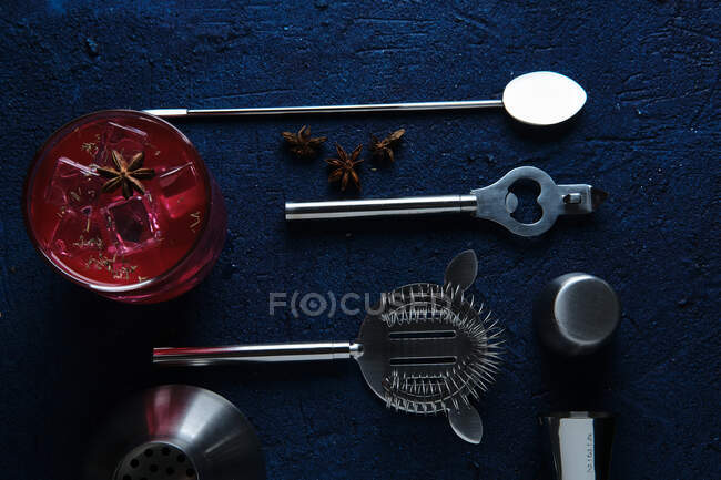 Délicieux cocktail rouge et outils de barman sur la table — Photo de stock