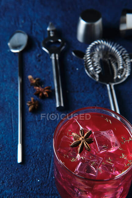 Вкусный красный коктейль и барменские инструменты на столе — стоковое фото