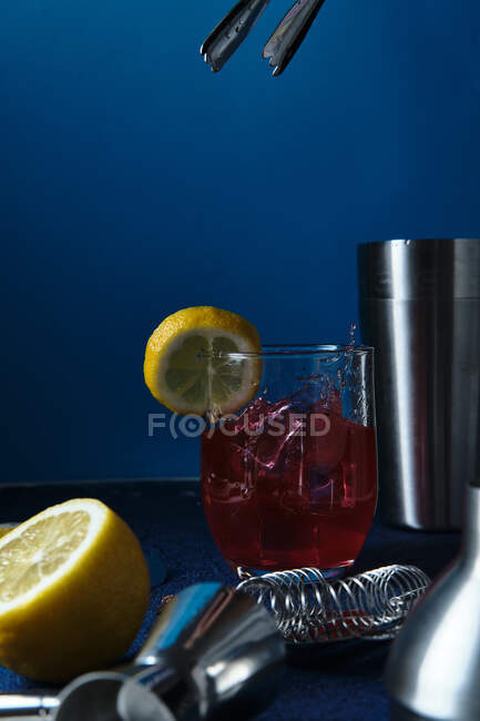 Delicious red cocktail and barman tools on table — Stock Photo