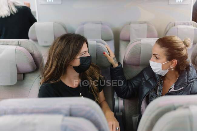 Mujeres con máscara sentadas en aviones - foto de stock