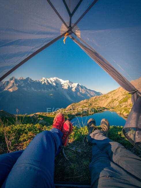 Turistas relaxados deitados em tenda em montanhas nevadas à luz do sol — Fotografia de Stock