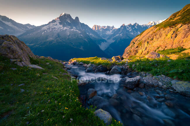 Desde arriba claro pequeño río que fluye a través del fondo de piedra en las montañas en el día soleado en Chamonix, Mont-Blanc - foto de stock