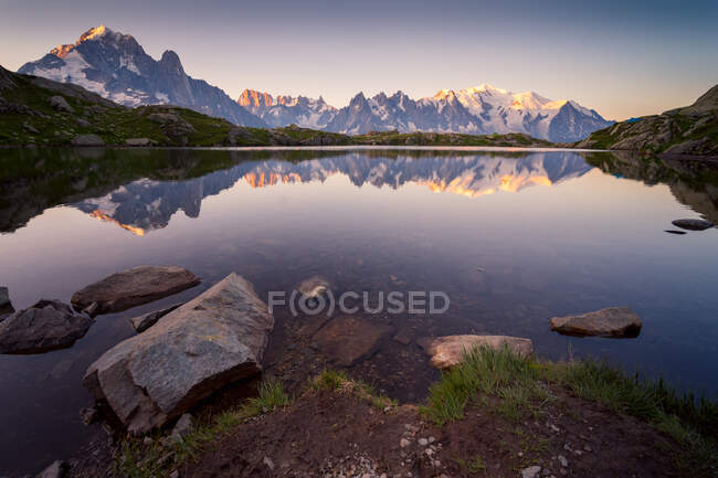 Lago di cristallo che riflette montagne innevate in giorno luminoso — Foto stock
