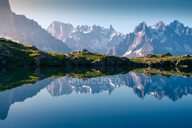 Lac cristallin reflétant les montagnes enneigées par beau temps — Photo de stock