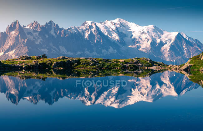 Gama de picos nevados brancos e à beira-mar montanhoso refletindo em claro lago imóvel em dia ensolarado em Chamonix, Mont-Blanc — Fotografia de Stock