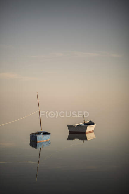 Ainda barcos sobre o céu pastel e oceano calmo vazio à beira-mar — Fotografia de Stock