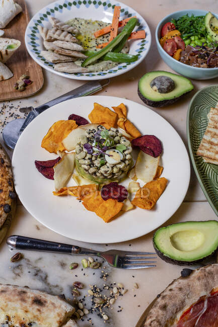 De cima do prato de feijão com pétalas na chapa perto de garfo com faca e pizza na mesa — Fotografia de Stock