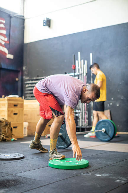 Спортивний спортсмен регулює ваги на штангах — стокове фото