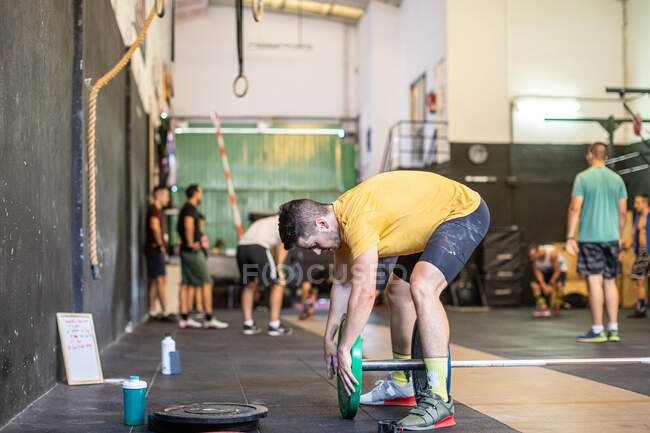 Athlete adjusting weights on barbells — Stock Photo