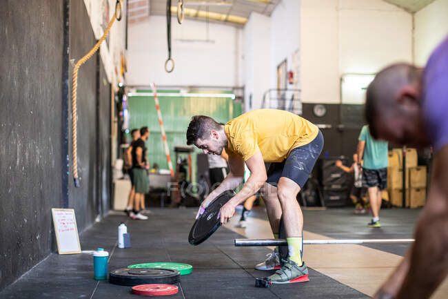 Athlete adjusting weights on barbells — Stock Photo