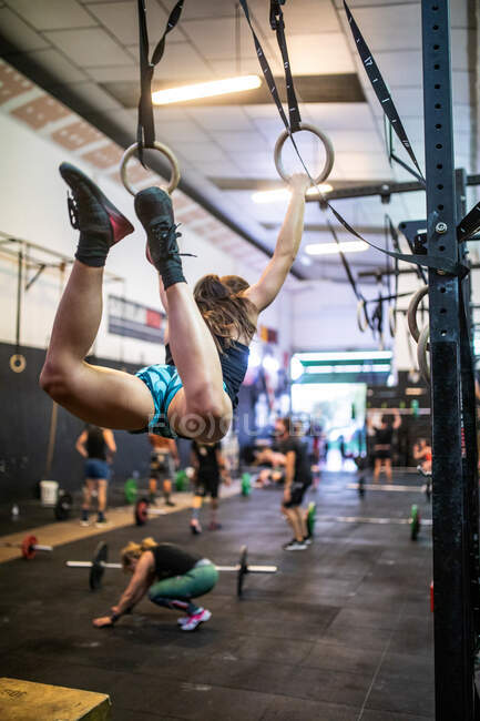 Sportswoman training on gymnastic rings in modern gym — Stock Photo