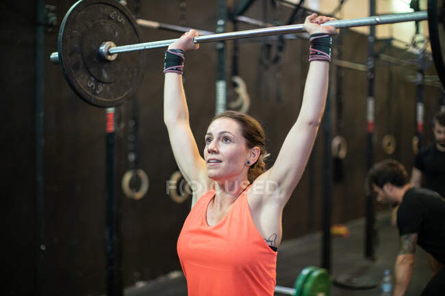 Woman lifting barbell in gym — Stock Photo