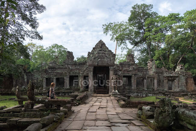 Vista laterale della donna che si gode le vacanze guardando le rovine del tempio religioso di Angkor Wat in Cambogia — Foto stock