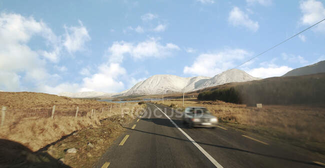 Paesaggio panoramico di auto a cavallo su strada asfaltata attraverso le montagne in Irlanda — Foto stock