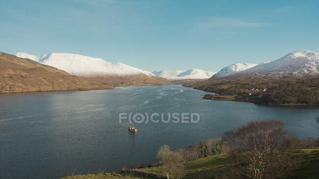 D'en haut paysage pittoresque de bateau solitaire flottant dans le lac dans les montagnes enneigées en Irlande — Photo de stock