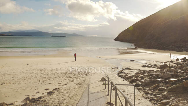 Back view of faceless tourist contemplating nature landscape while standing on sandy beach on coastline of Ireland — Stock Photo