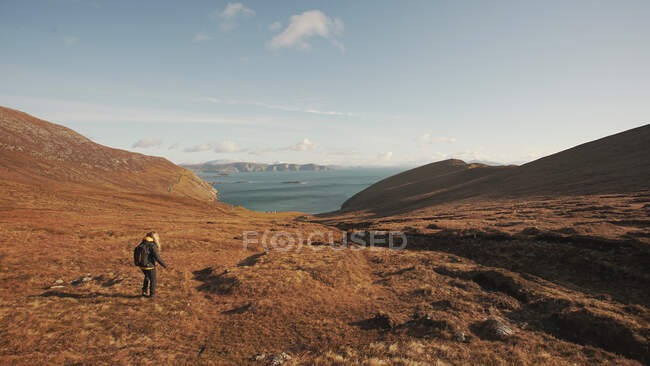 Back view of unrecognizable woman walking on wonderful nature landscape and sea while standing on cliff in Ireland looking away — Stock Photo