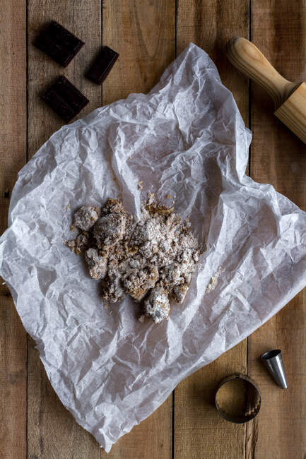 De cima de massa de chocolate em papel de cozimento branco moldes de biscoito de metal de chocolate e rolo de pino na mesa de madeira — Fotografia de Stock