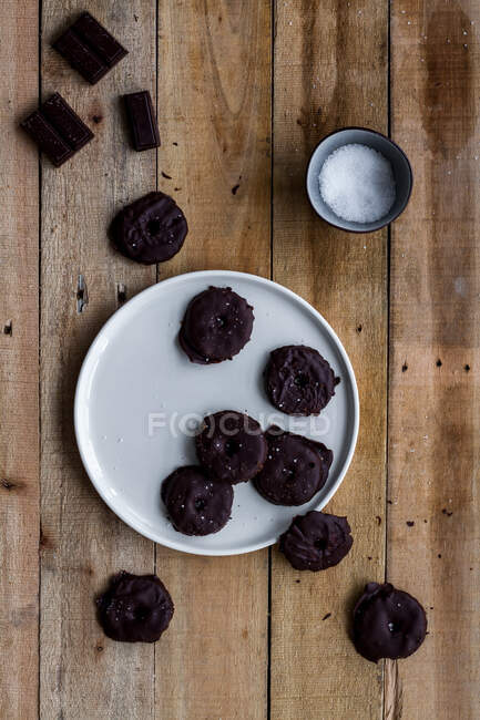 De arriba las galletas aromáticas cubiertas con el jarabe de chocolate en el plato blanco sobre la mesa de madera - foto de stock