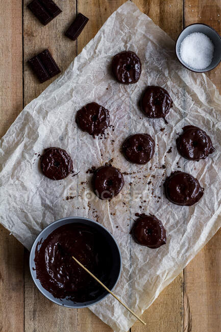 Von oben Ernte Koch gießt gebackene leckere Plätzchen mit Schokoladensirup in Backpapier auf Holztisch — Stockfoto