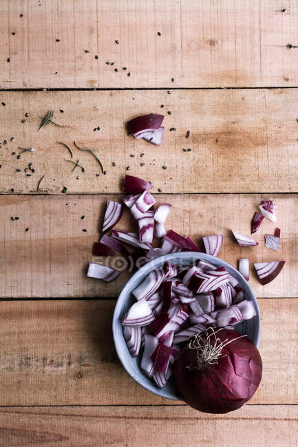 Draufsicht auf rohe gehackte rote Zwiebel in Schüssel und auf rustikalen Holztisch — Stockfoto