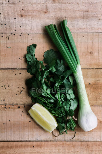 Vista superior de cebola verde fresca crua e molho de salsa com quarto de limão em mesa rústica de madeira — Fotografia de Stock
