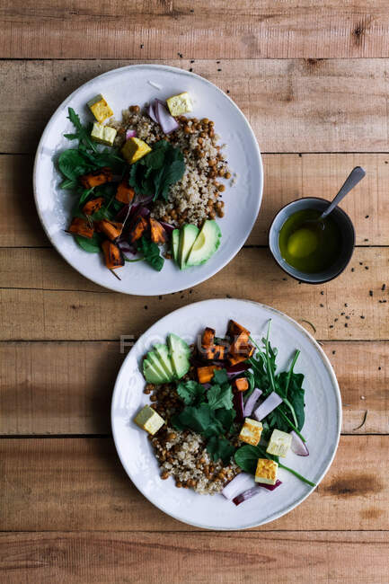 Vista superior de la comida vegetariana con diferentes verduras y arroz en platos en mesa de madera rústica - foto de stock