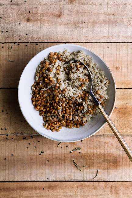 Von oben weißer Reis gemischt mit Bohnen in Schüssel mit Löffel auf rustikalem Holztisch — Stockfoto