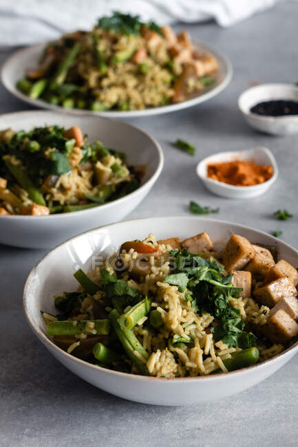 Сверху на тарелках подают вкусное блюдо с рисом и зеленой фасолью с приправами на столе — стоковое фото