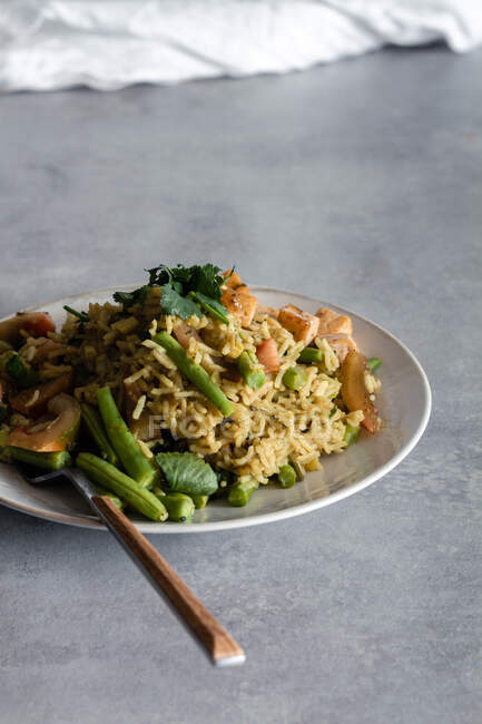 Von oben leckeres gekochtes Gericht mit Reis und grünen Bohnen, serviert auf Tellern mit Gewürzen auf dem Tisch — Stockfoto