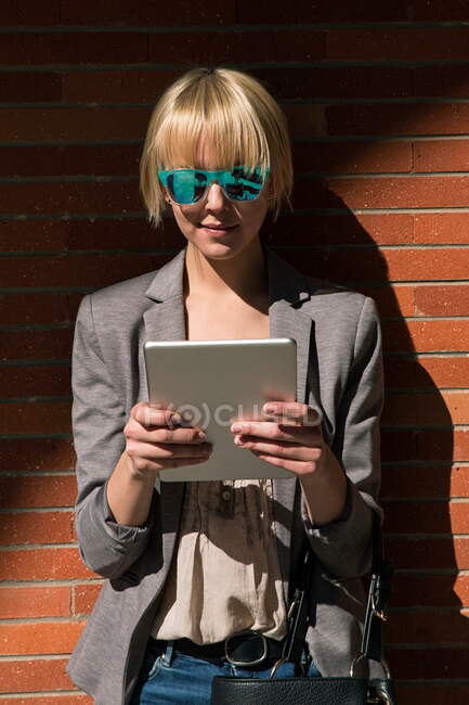 Businesswoman with tablet at wall — Stock Photo