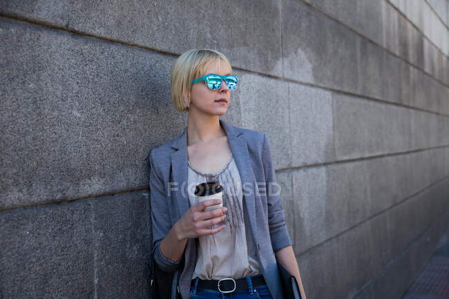 Businesswoman with coffee at wall — Stock Photo
