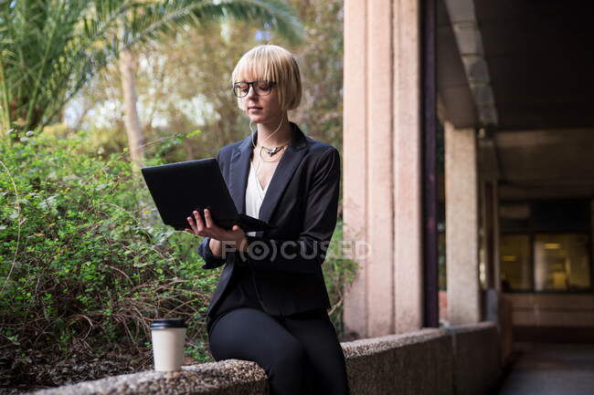 Joven empresaria sentada y usando tableta - foto de stock