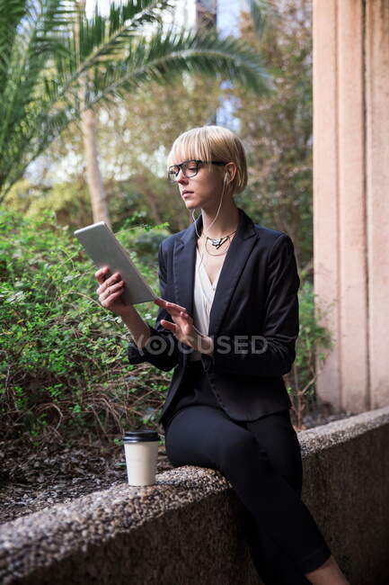 Jeune femme d'affaires assise et utilisant une tablette — Photo de stock