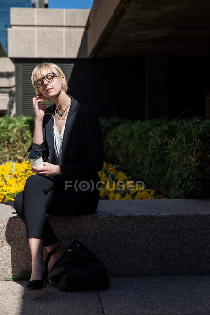 Молода бізнес-леді сидить і слухає музику — стокове фото