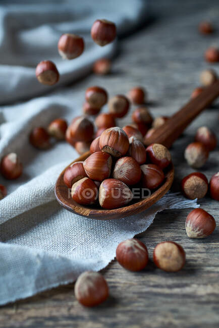 Сверху вкусные свежие собранные лесные орехи на деревянной ложке на постельном белье за столом — стоковое фото