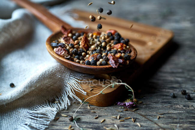 Spice fragrant mix of fresh spices and dried berries on wooden spoon on linen on wooden stand at table — Stock Photo