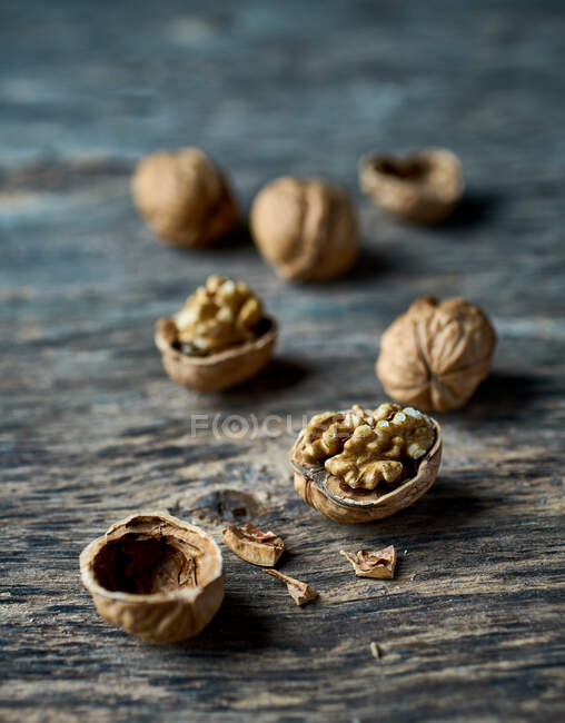 D'en haut appétissantes noix demi-pelées jaunes fraîches et coquilles de noix vides cassées sur une table en bois — Photo de stock