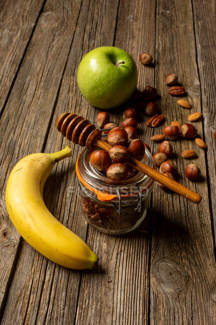 Maçã e banana com nozes na mesa de madeira — Fotografia de Stock