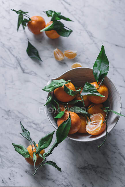 Orangene Mandarinen in Keramik-Zierschale auf Marmortisch — Stockfoto