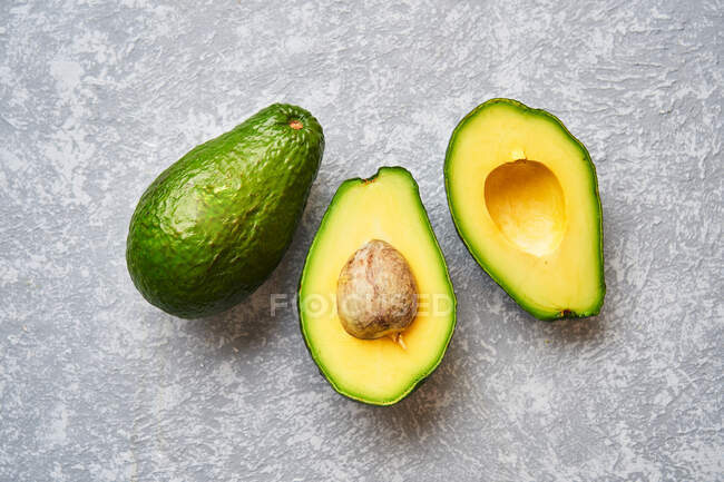 Cut avocado on grey texture background — Stock Photo