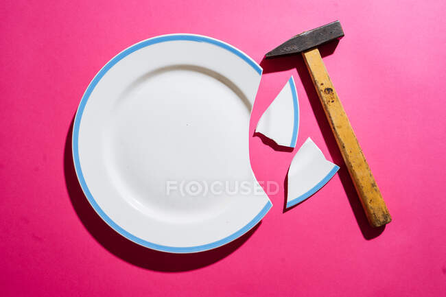 Разбитая белая тарелка на розовом фоне — стоковое фото